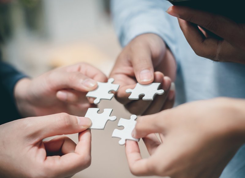 vier Teammitglieder halten Puzzleteile in der Hand