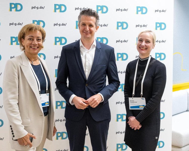Yvonne Balzer (PD-Standortleitung), Dr. Bernd Schulte (Staatssekretär, Staatskanzlei des Landes Nordrhein-Westfalen) und Theresa Twachtmann (Geschäftsführerin der PD), Birte Frischemeier (Mitglied der PD-Geschäftsleitung) vor einer PD-Logo-Wand Yvonne Balzer (Mitglied der PD-Geschäftsleitung), Dr. Bernd Schulte (Staatss vor einer PD-Logo-Wand Yvonne Balzer (Mitglied der PD-Geschäftsleitung), Dr. Bernd Schulte (Staatssekretär, Staatskanzlei des Landes Nordrhein-Westfalen) und Theresa Twachtmann (Geschäftsführerin der PD) vor einer PD-Logo-Wand