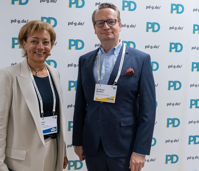 Yvonne Balzer (PD-Standortleitung) und Dr. Michael Rauterkus (Leitung, Rechenzentrum der Finanzverwaltung NRW) vor einer PD-Logo-Wand