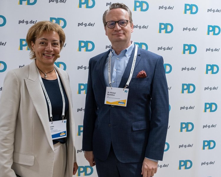 Yvonne Balzer (PD-Standortleitung) und Dr. Michael Rauterkus (Leitung, Rechenzentrum der Finanzverwaltung NRW) vor einer PD-Logo-Wand