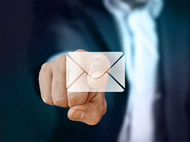 Mann im Anzug zeigt mit dem Finger auf ein E-Mail Symbol