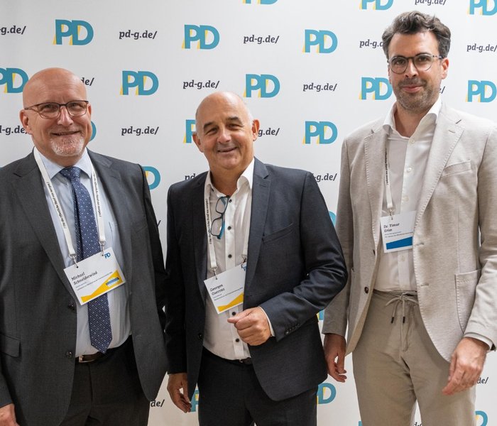 Michael Schneiderwind (Abteilungsleitung, Landesamt zur Bekämpfung der Finanzkriminalität NRW), Georges Guerraz (Fachreferent, Rechenzentrum der Finanzverwaltung NRW) und Dr. Timur Erim (Senior Managing Expert, PD – Berater der öffentlichen Hand GmbH) vor einer PD-Logo-Wand