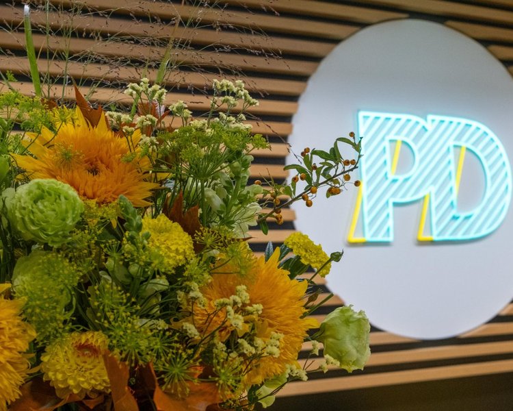 Eingangsbereich des PD-Büros mit PD-Logo und einem Blumenstrauß