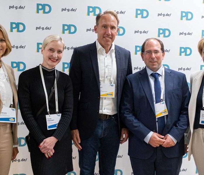 Birte Frischemeier (PD-Standortleitung), Theresa Twachtmann (Geschäftsführerin der PD), Reinhard Derix (Oberfinanzpräsident, Oberfinanzdirektion NRW), Dr. Robin Fink (Referatsleitung, Ministerium der Finanzen des Landes Nordrhein-Westfalen) und Yvonne Balzer (PD-Standortleitung) vor einer PD-Logo-Wand