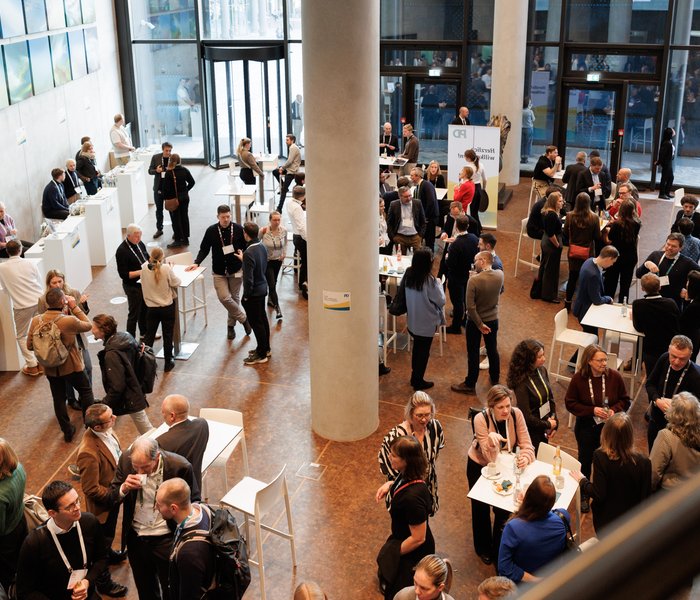 PD-Mitarbeitende stehen zusammen an Stehtischen und unterhalten sich im Foyer einer Firmenevent location
