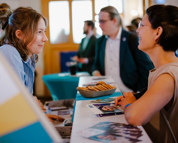 Eine PD-Mitarbeiterin und eine interessierte Person unterhalten sich. Sie stehen sich am PD-Stand gegenüber.